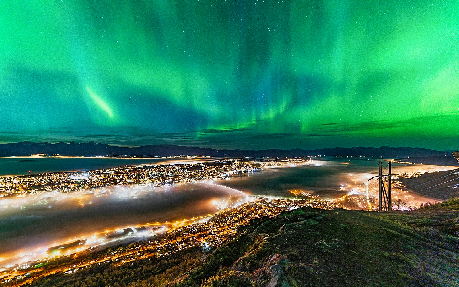 Northern lights over Tromso cityscape at night.