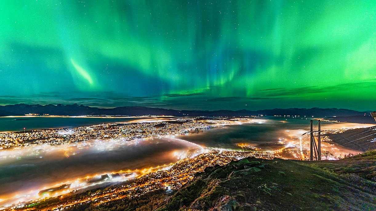 Northern lights over Tromso cityscape at night.