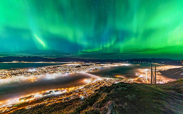 Northern lights over Tromso cityscape at night.