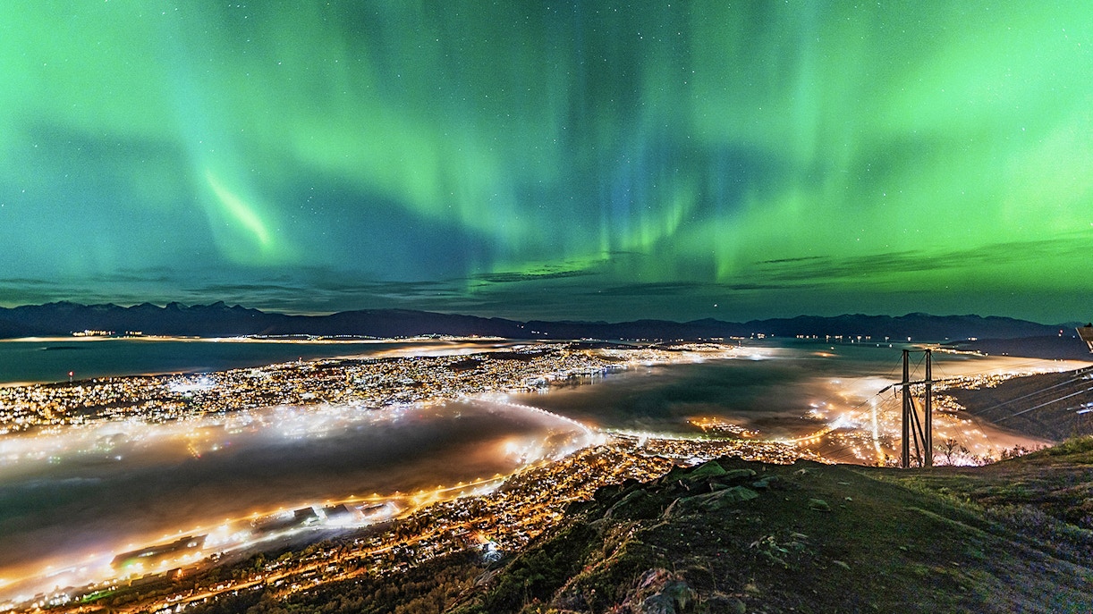 Northern lights over Tromso cityscape at night.
