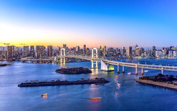 Tokyo Bay with Rainbow Bridge and city skyline at dusk.