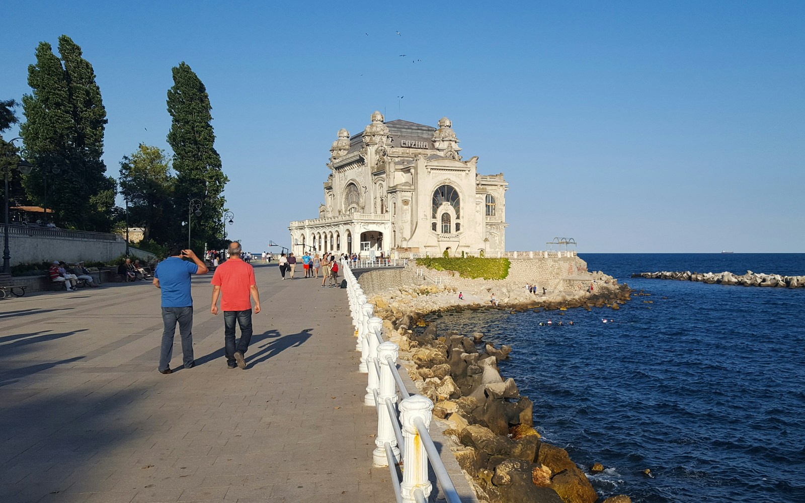 Constanta Casino by the Black Sea with people walking along the promenade.