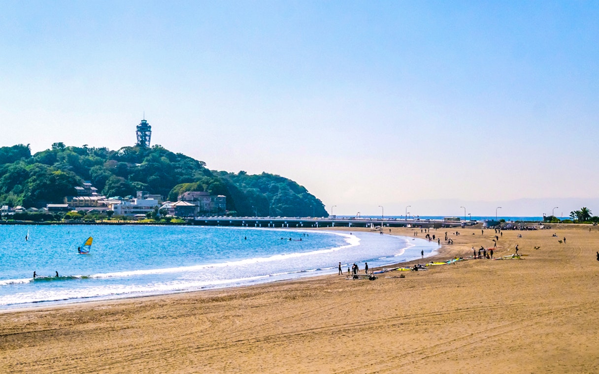 Beachgoers and surfers at Shonan Coast, Kamakura with Enoshima Island in the background.