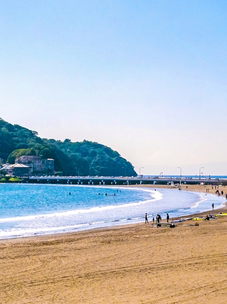 Beachgoers and surfers at Shonan Coast, Kamakura with Enoshima Island in the background.