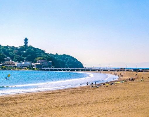 Beachgoers and surfers at Shonan Coast, Kamakura with Enoshima Island in the background.