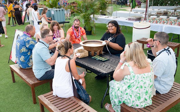 Guests participating in a traditional food-making activity at Mauka Warriors Luau, Hawaii.