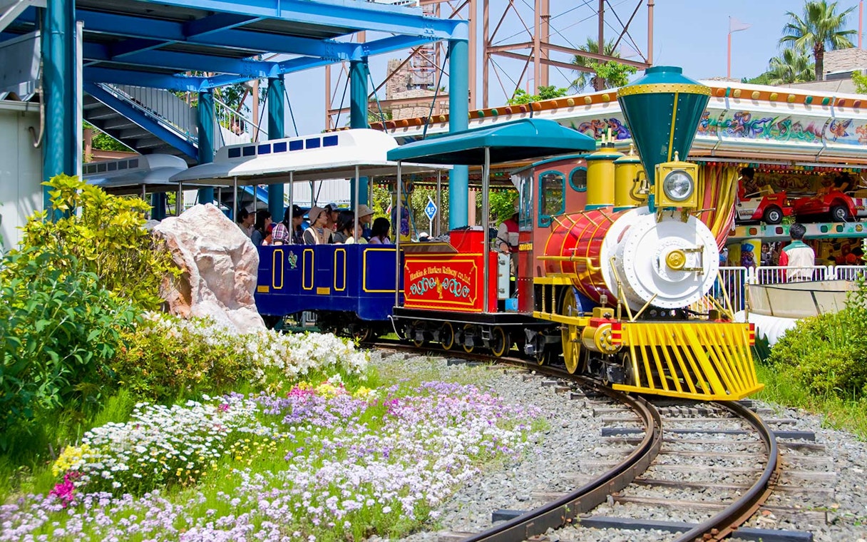 Colorful train ride at Hirakata Park, Japan, surrounded by flowers and greenery.
