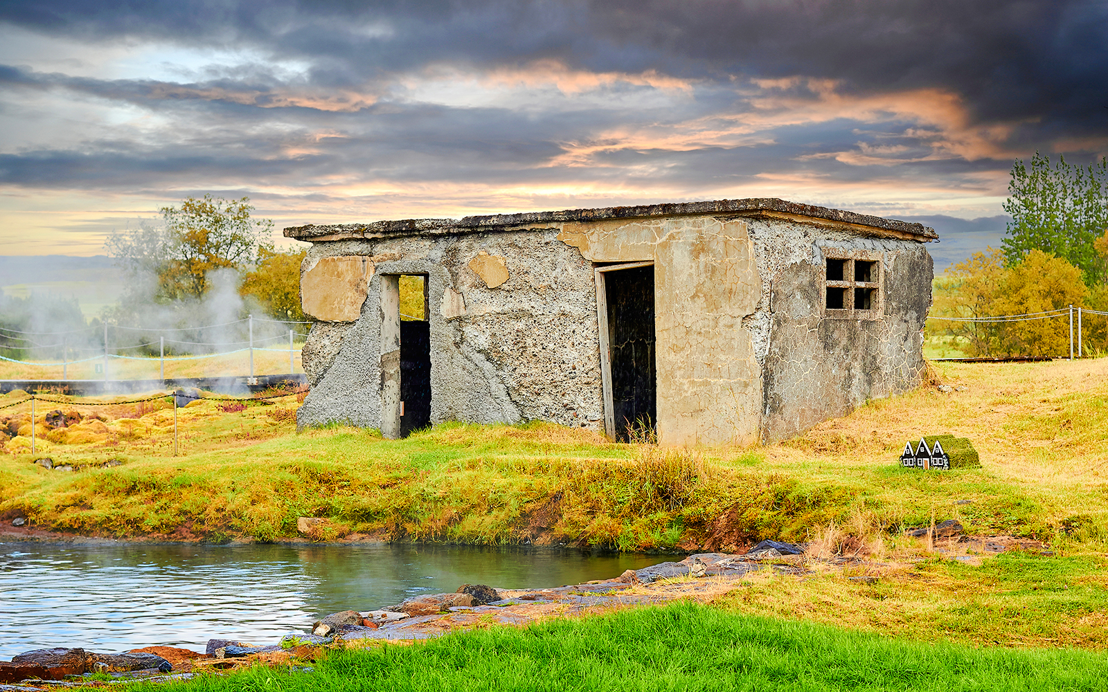 Old stone building near the Secret Lagoon in Iceland with geothermal steam rising.