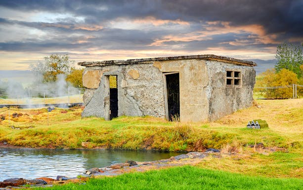 Old stone building near the Secret Lagoon in Iceland with geothermal steam rising.
