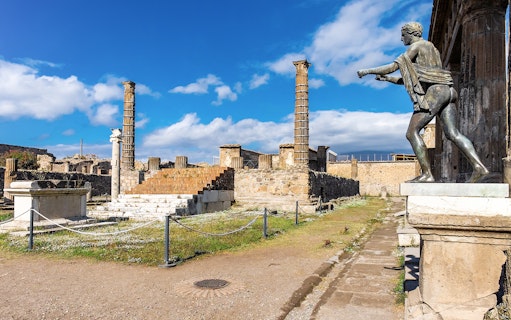 Temple of Apollo ruins with statue and columns in Pompeii, Italy.