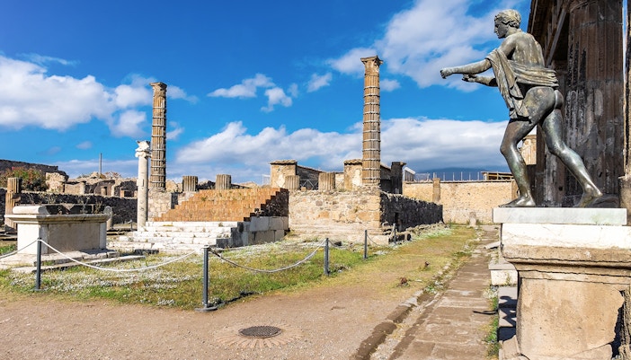 Temple of Apollo ruins with statue and columns in Pompeii, Italy.