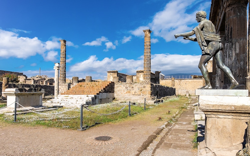 Temple of Apollo ruins with statue and columns in Pompeii, Italy.