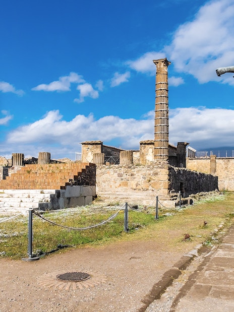 Temple of Apollo ruins with statue and columns in Pompeii, Italy.