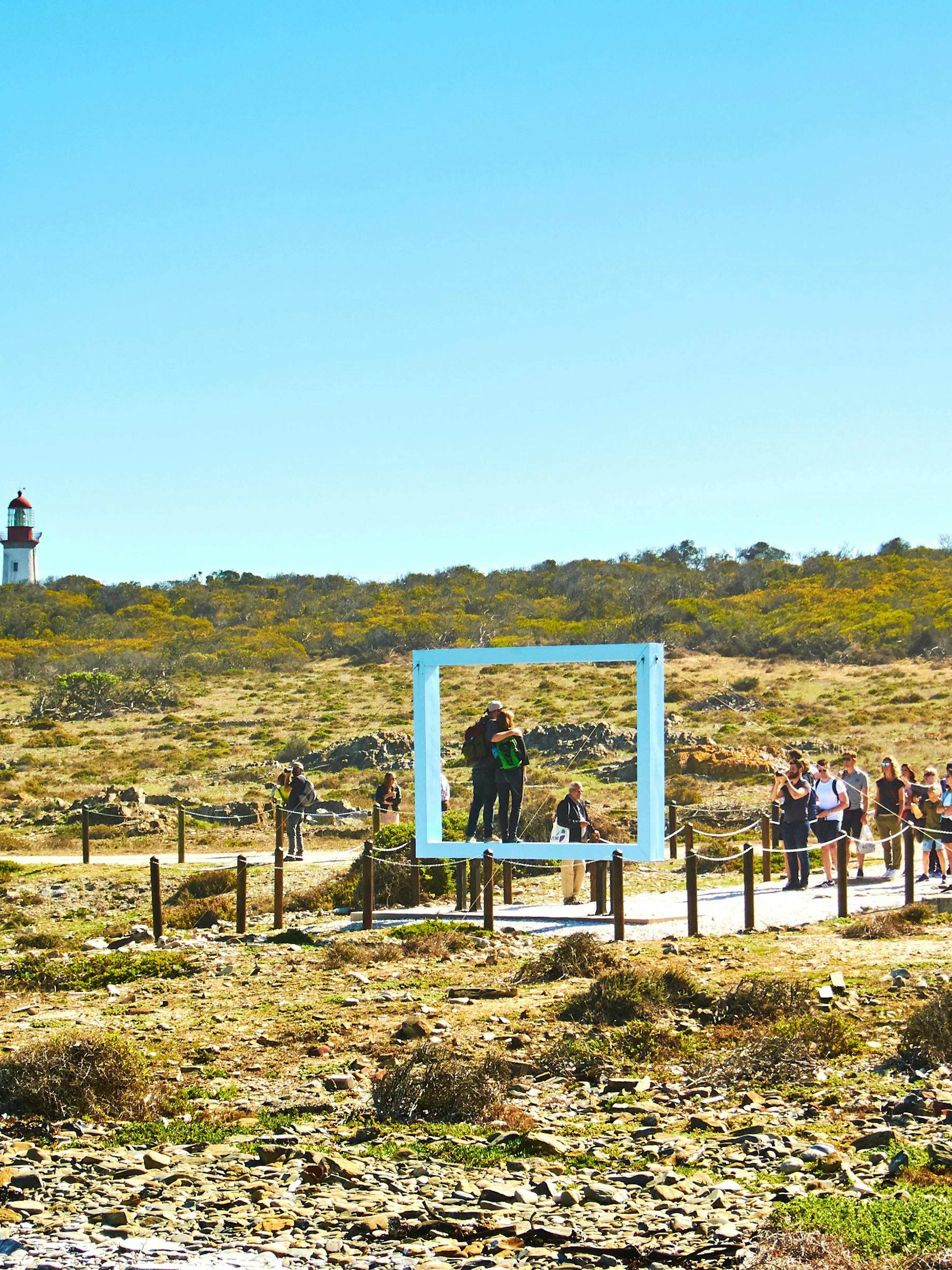Tourists exploring Robben Island with a lighthouse in the background.