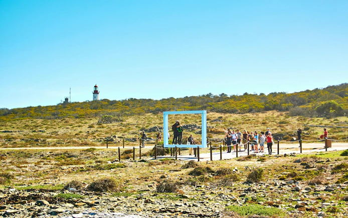 Tourists exploring Robben Island with a lighthouse in the background.