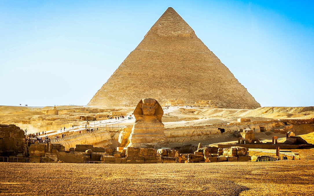 Pyramid of Giza and Sphinx with tourists exploring the site in Egypt.