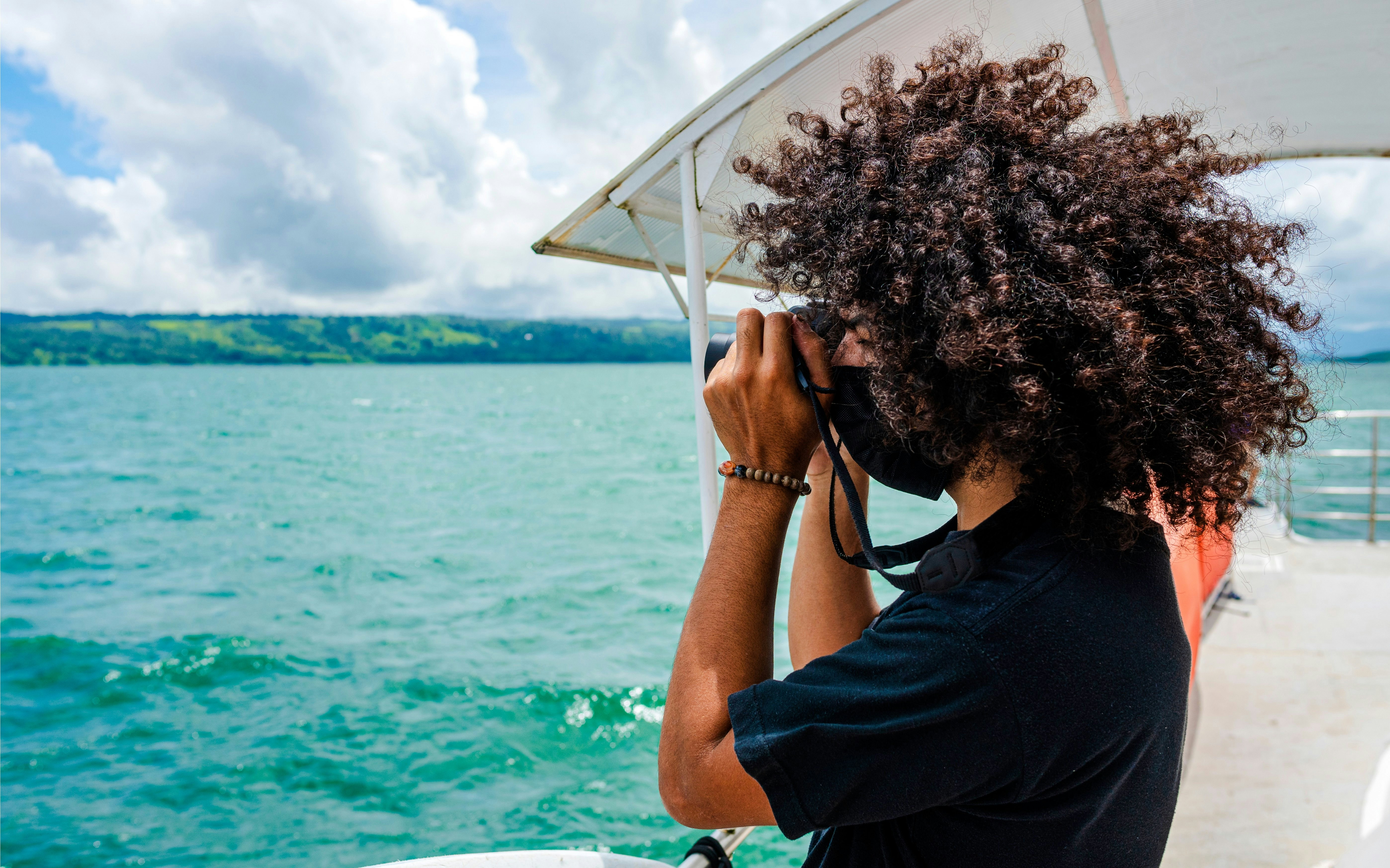 Young man photographing from a catamaran on a lake.
