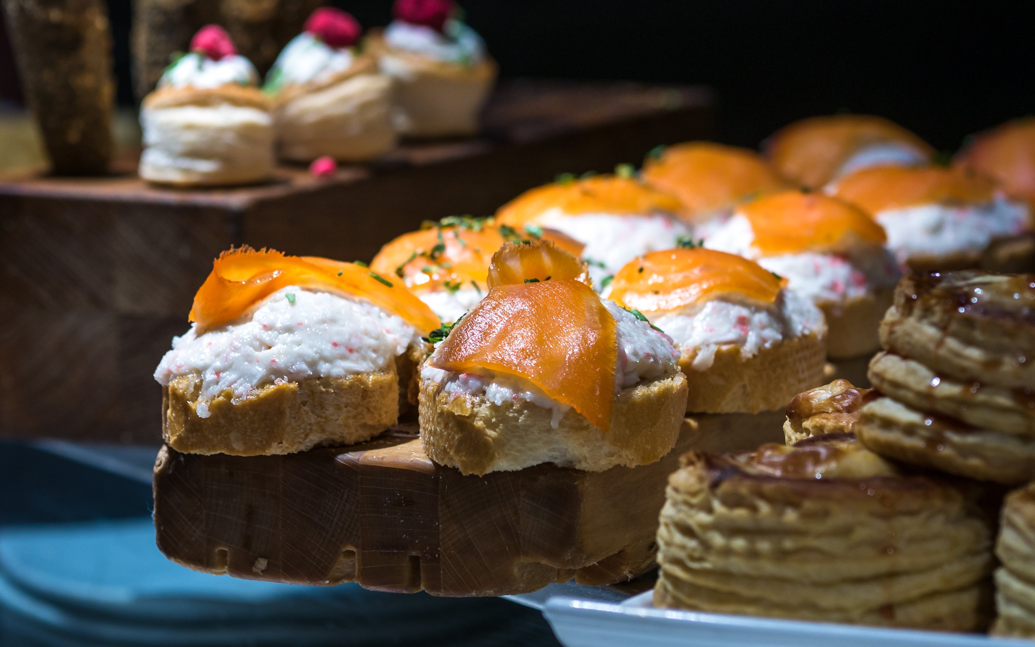 Salmon and crayfish tapas on bread slices, garnished with herbs.