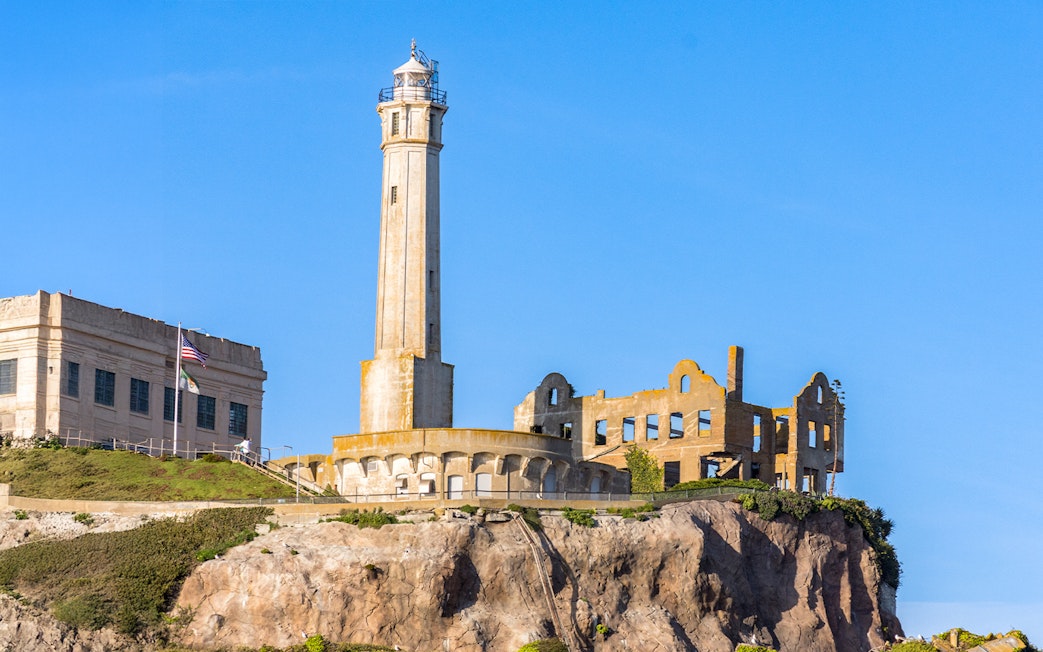 Alcatraz Island lighthouse and ruins at sunset viewed from the bay.