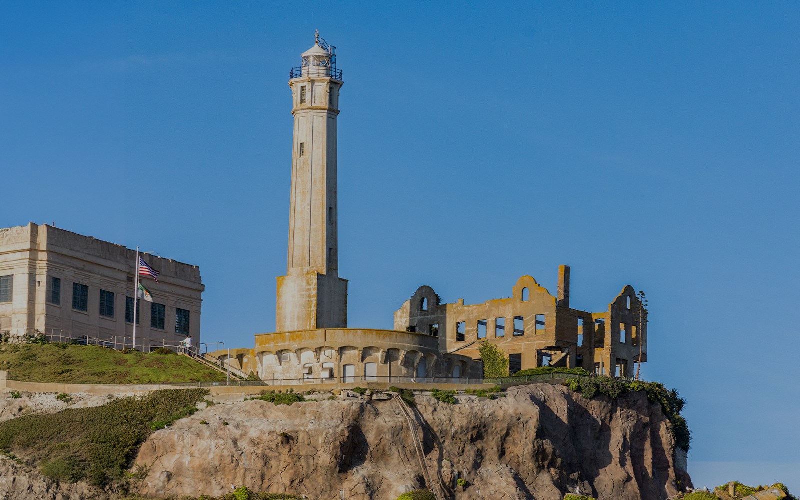 Alcatraz Island lighthouse and ruins at sunset viewed from the bay.