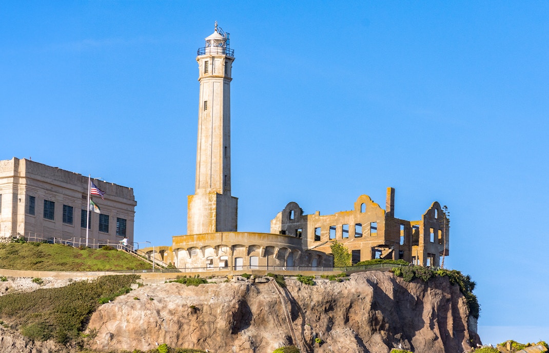 Alcatraz Island lighthouse and ruins at sunset viewed from the bay.