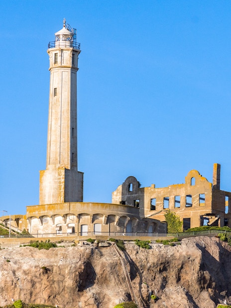 Alcatraz Island lighthouse and ruins at sunset viewed from the bay.