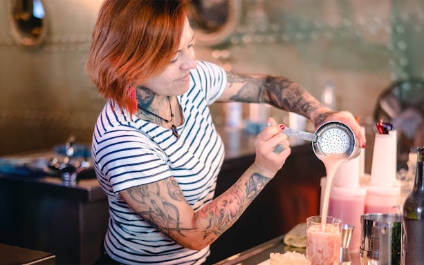 Bartender pouring drinks at Berlin Icebar with ice sculptures in the background.