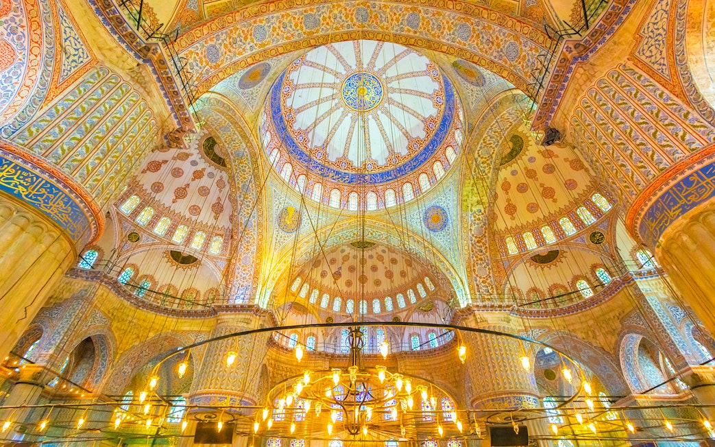 Interior of the Blue Mosque in Istanbul, showcasing intricate domed ceiling and ornate designs.
