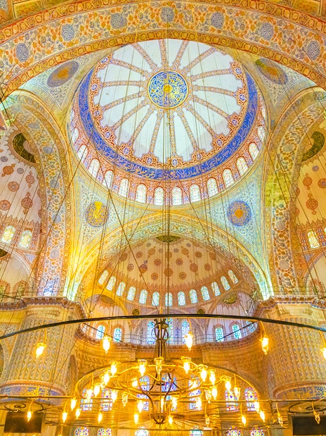 Interior of the Blue Mosque in Istanbul, showcasing intricate domed ceiling and ornate designs.