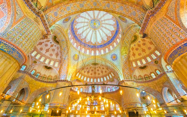 Interior of the Blue Mosque in Istanbul, showcasing intricate domed ceiling and ornate designs.