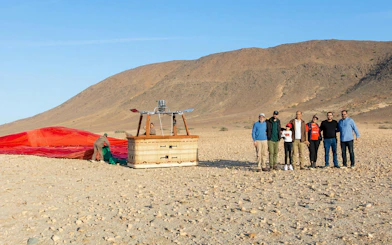 Hot air balloon preparation in Marrakech desert with group of people nearby.