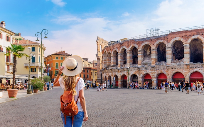 Girl with backpack facing Verona Arena in Italy.