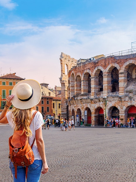 Girl with backpack facing Verona Arena in Italy.