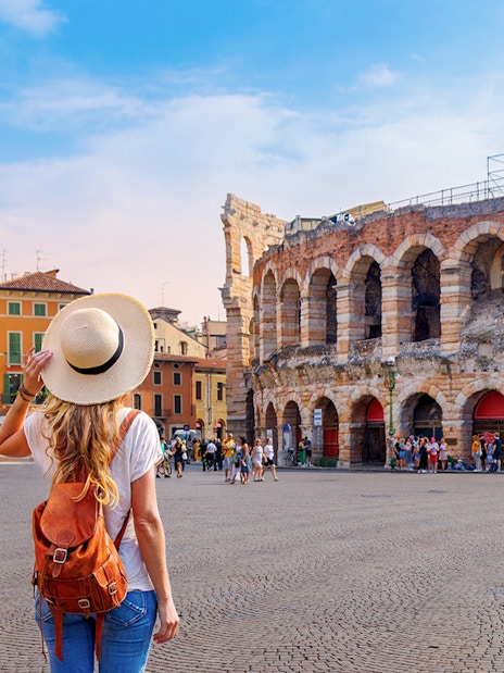 Girl with backpack facing Verona Arena in Italy.