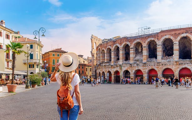 Girl with backpack facing Verona Arena in Italy.