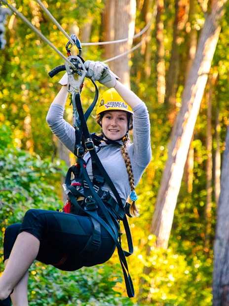Guest zip lining through forest on Kohala Canopy Adventure.