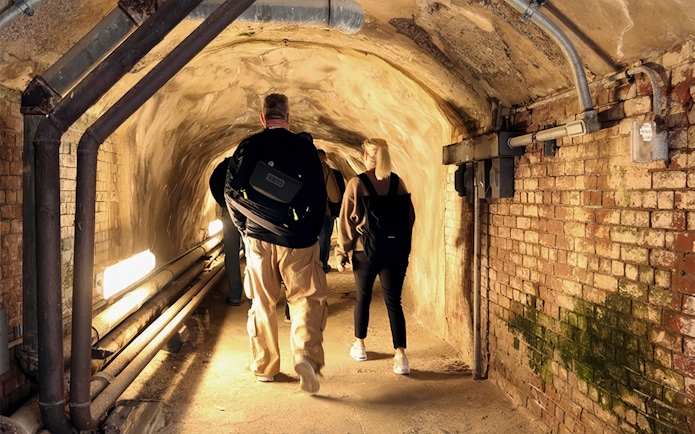 Visitors exploring a narrow underground tunnel on Alcatraz Island.