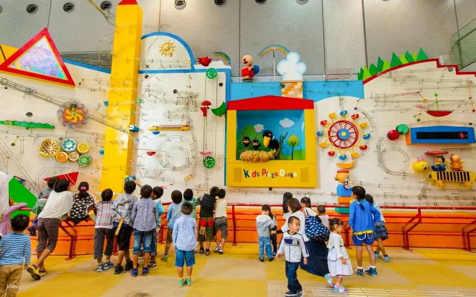 Children exploring interactive wall exhibit at Kids Plaza Osaka.