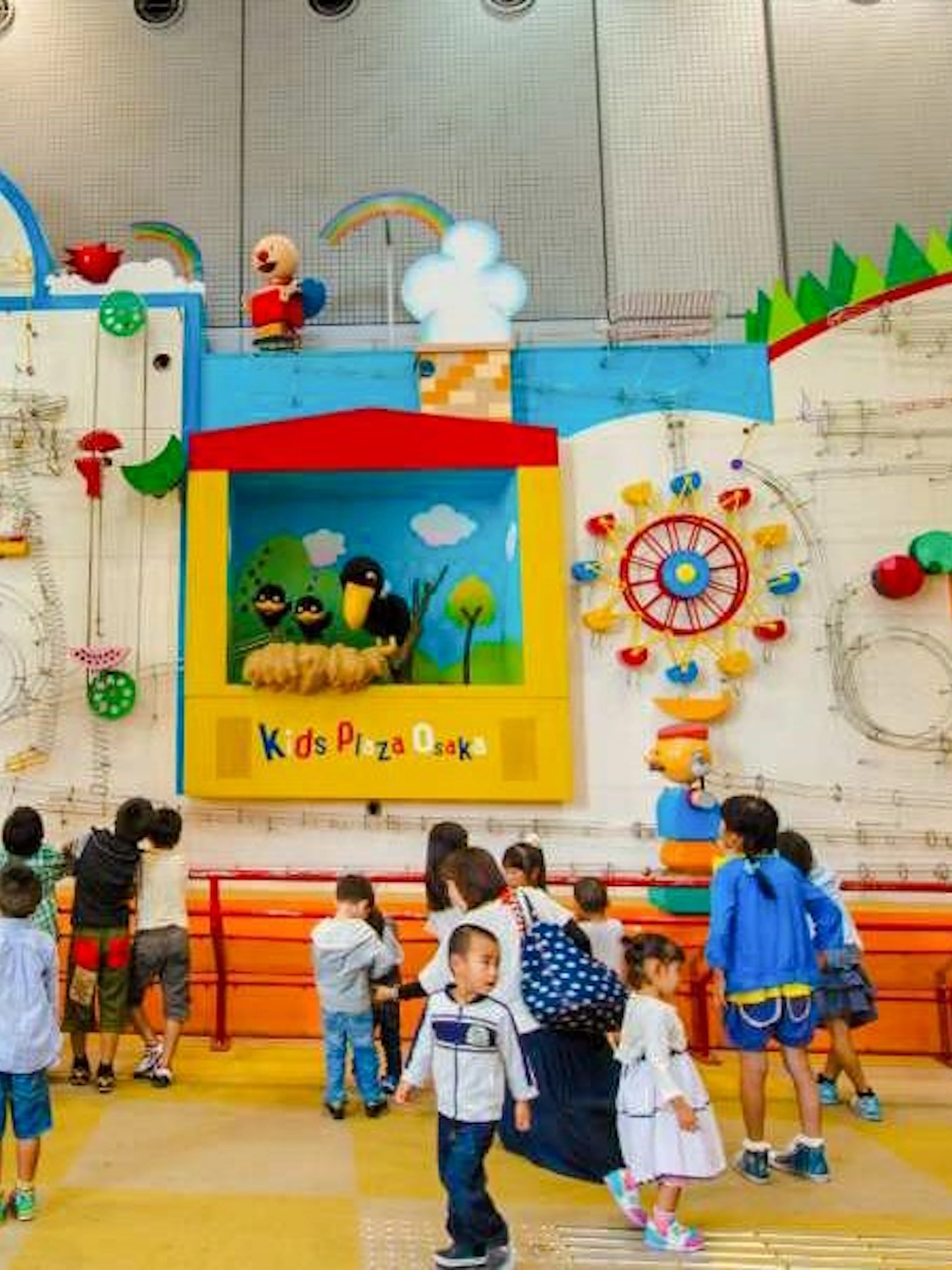 Children exploring interactive wall exhibit at Kids Plaza Osaka.