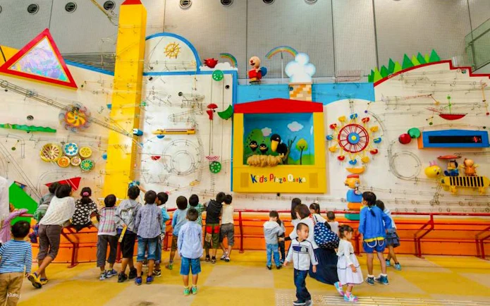 Children exploring interactive wall exhibit at Kids Plaza Osaka.
