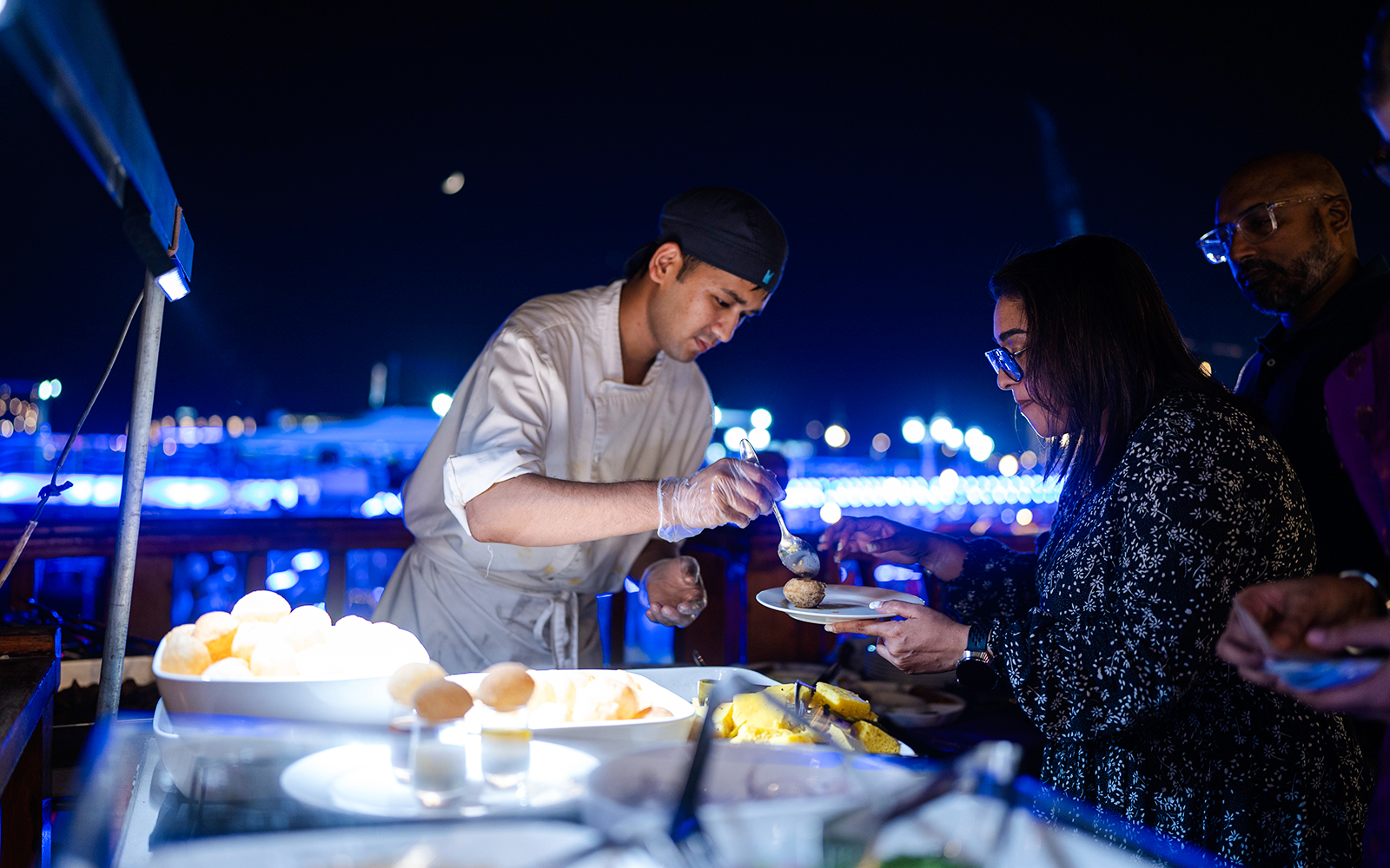 Chef serving Indian dinner on Dubai Marina luxury dhow cruise.