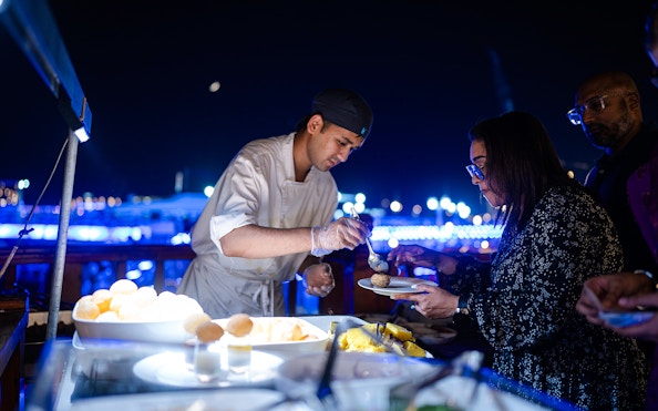 Chef serving Indian dinner on Dubai Marina luxury dhow cruise.
