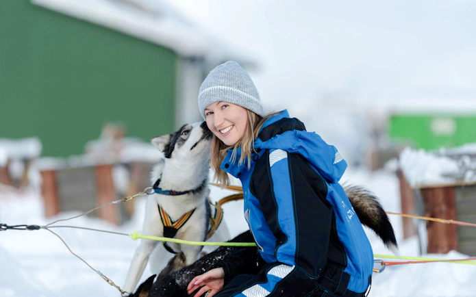 Guests interacting with a sled dog during a kennel visit in Tromso.