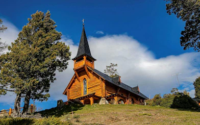 Historic San Eduardo Chapel on Circuito Chico, surrounded by mountains and forests.