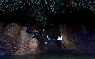 Person black water rafting under glowworms in Waitomo cave.