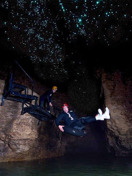 Person black water rafting under glowworms in Waitomo cave.