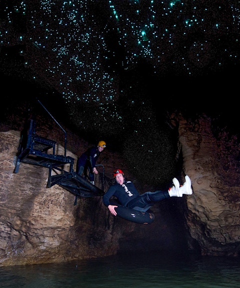 Person black water rafting under glowworms in Waitomo cave.