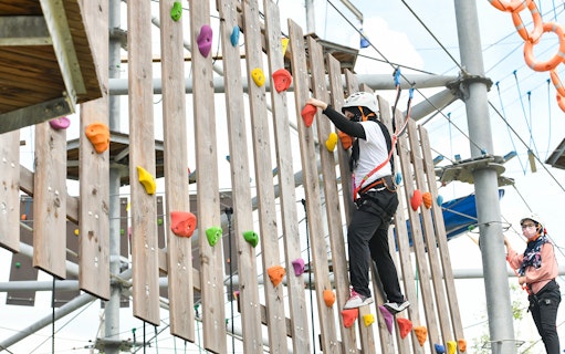 Person climbing a wooden wall with colorful holds at Discovery Park, Gamuda Cove.