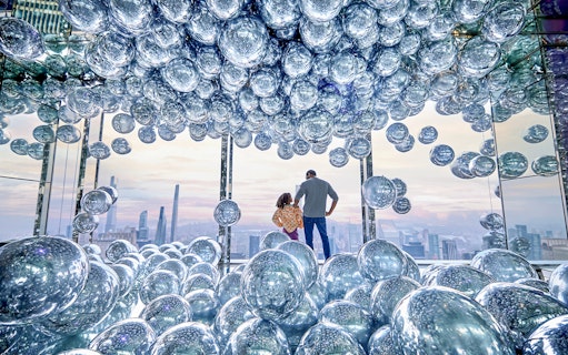 Visitors at SUMMIT One Vanderbilt surrounded by reflective spheres with a cityscape view.
