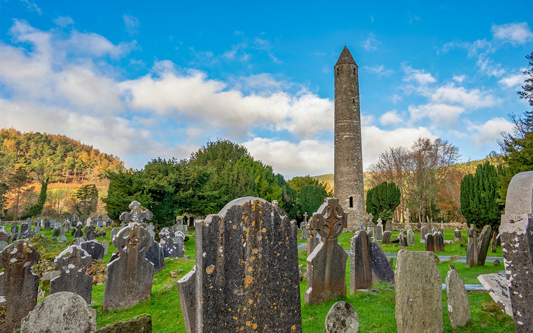Glendalough Monastic site with round tower and ancient gravestones in a lush valley.